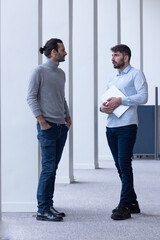 deux jeune hommes d'affaire ou employés de bureau discutent debout dans les locaux de leur...