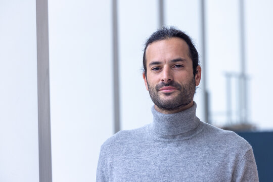 portrait d'un beau jeune homme de 35 ans souriant et pensif. C'est un employ&eacute; qui pose dans les bureaux de son entreprise