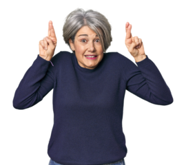 Caucasian mid-age female on studio background crossing fingers for having luck