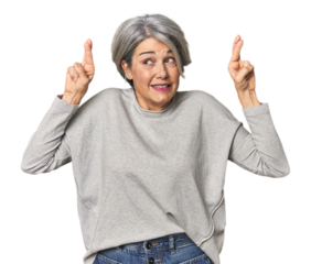 Caucasian mid-age female on studio background crossing fingers for having luck