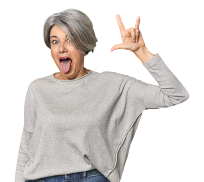 Caucasian mid-age female on studio background showing a horns gesture as a revolution concept.
