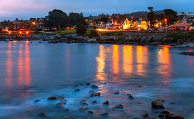 Evening mood at “Lovers Point” in Pacific Grove, a small town on the Pacific coast near Monterey, California (USA). Twilight atmosphere after sunset with illuminated promenade and long exposure.
