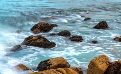 Long exposure of splashing breaking waves on the coast of California (USA). Shell-covered rocks and...