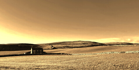 Early winter landscape over Malham Moor, with rolling hills and a vast sky with a solitary house...