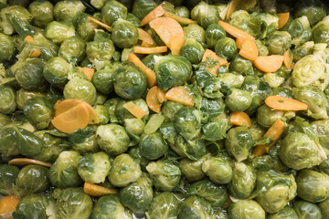 A lot of boiled brussel sprouts with carrot slices as garnish and side dish. Vegetables vegan food