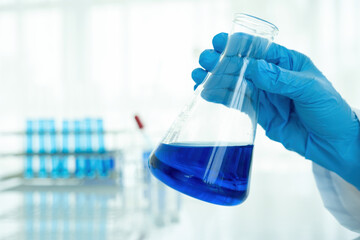 Medical or scientific researcher or man doctor looking at a test tube of clear solution in a laboratory