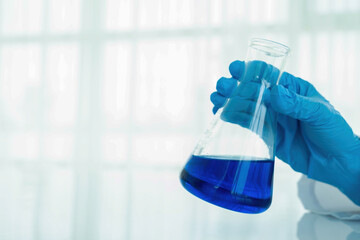 Medical or scientific researcher or man doctor looking at a test tube of clear solution in a laboratory