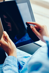 Cropped view of hipster girl touching with finger on display of modern touch pad device sitting in tram transport and using free public internet.Woman's hands holding digital tablet