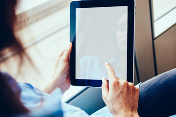Woman's hands holding tablet with mock up screen for advertisement and installing application via free 4G internet connection sitting in tram.Hipster girl touching with finger on copy space area