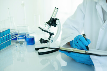 Medical or scientific researcher or man doctor looking at a test tube of clear solution in a...
