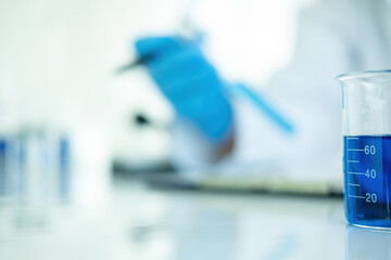 Medical or scientific researcher or man doctor looking at a test tube of clear solution in a laboratory