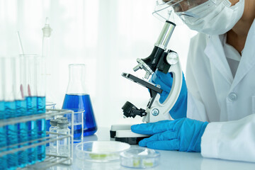 Fototapeta premium Medical or scientific researcher or man doctor looking at a test tube of clear solution in a laboratory