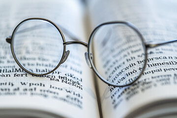 A pair of glasses is sitting on top of a book - Powered by Adobe