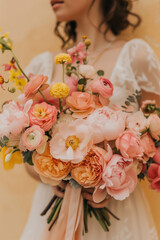 Luxurious wedding bouquet of ranunculus, peonies, chrysanthemums and roses in the hands of a bride in a wedding dress.