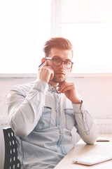 Confident male programmer talking with operator for checking account balance looking at camera while sitting indoors with computer with blank screen for your internet advertising on background