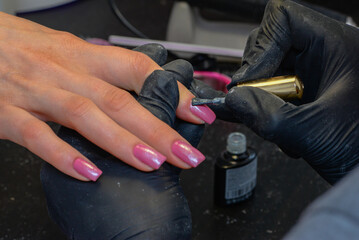 Close-up manicure process, female hands painting nails
