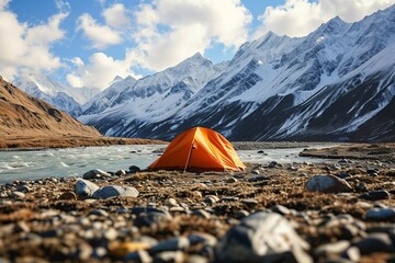 A bright tent on the river bank against the backdrop of the mountains. Concept of tourism, vacation, travel, hiking