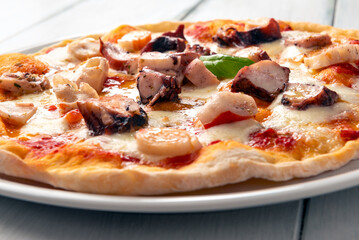Deliziosa pizza mediterranea condita con mozzarella, sugo, polpi e surimi, cibo italiano 