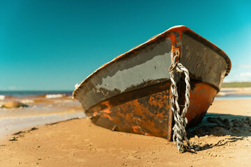 Old fishing boat rusting on sandy shore under sunny skies