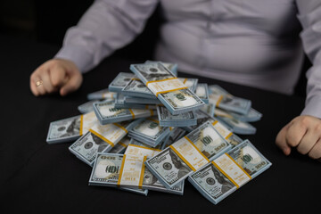 There are bundles of money on the black table. A man and a pile of money on a black background....