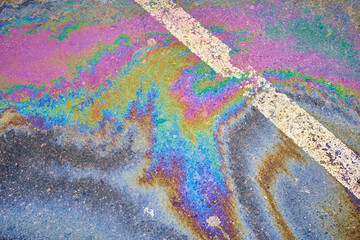 Oil spill on wet asphalt, parking lot with dividing lines. Highlighting environmental challenges...