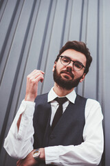 Portrait of handsome caucasian hipster guy casual dressed looking at camera near grey promotional background, young male student in spectacles for provide eyes protection posing near copy space area