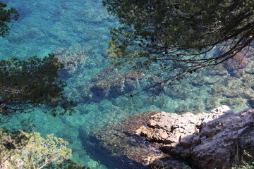 Natural and small coves of the Costa Brava with boats in the background and the blue sky with clouds and blue water. A beautiful place for vacations.