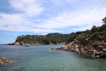 Naklejka premium Natural and small coves of the Costa Brava with boats in the background and the blue sky with clouds and blue water. A beautiful place for vacations.