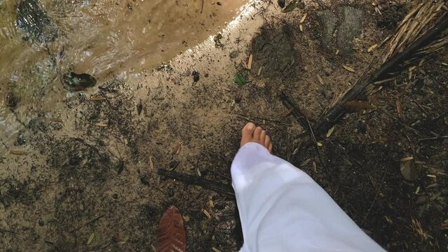 barefoot woman's feet walking towards the river. connection with nature for spiritual healing