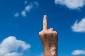 middle finger on the background of the sky. Insult. A hand showing the middle finger