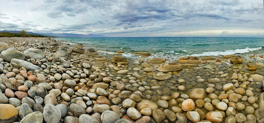 Northern Kyrgyzstan. The landscape of the cold Issyk-Kul lake with colored rounded stones of...