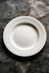 Simple white dinner plate on a textured dark stone countertop, spotlighting the plate for culinary branding or decorative art