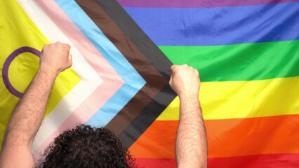 lgbtq+ pride 2024 protest concept. Male raises fists by new lgbt flag