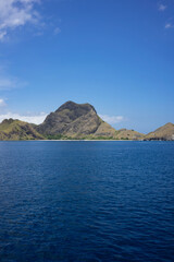 Fototapeta premium Majestic mountain peaks tower over the serene blue waters near Komodo Island, a gem in Indonesia's archipelago