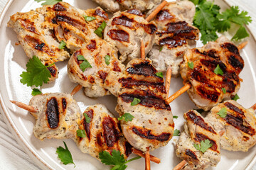 grilled mini pork skewers on a plate, top view