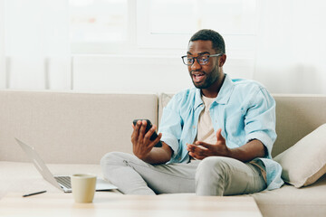 Smiling African American Man Working on Laptop at Home, Talking on Phone