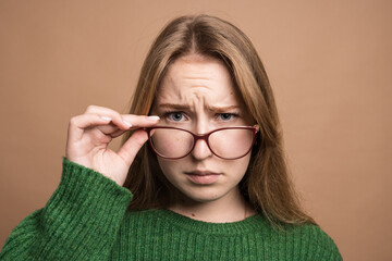 woman with poor vision on a isolated beige background, health problems astigmatism myopia