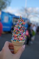 Hand holding ice cream cone with sprinkles