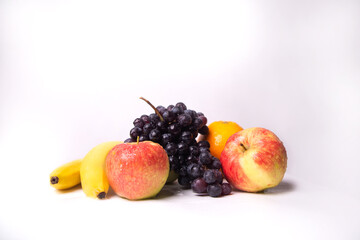 Still life of fruits on a white background, banana, apple, grapes