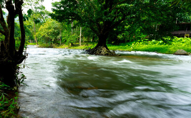 Leading lines and motion blur. The turbulent flow of dark water canal during the flood season in the countryside of Thailand.