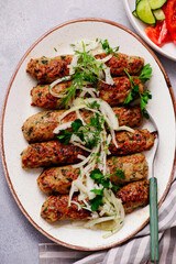Chicken Lula Kebab with  onions on a platter.top veiw