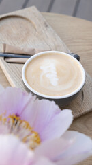 Coffee cup with pion. Cappuccino or latte on wooden table angle view.