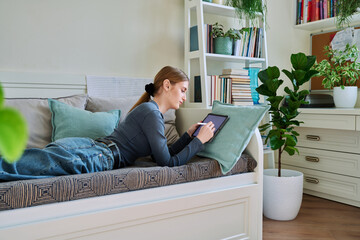 Young female teenager with digital tablet, stylus drawing illustrating at home