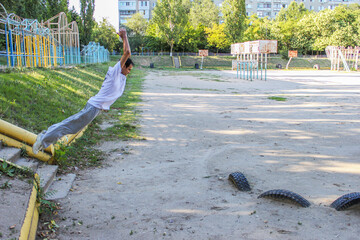 A guy in a light suit jumps over a long distance between the stairs and small tires in parkour...