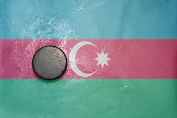 old hockey puck is on the ice with national flag of azerbaijan .