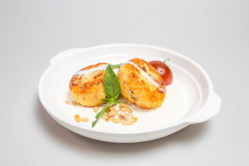 Fried cheese pancakes with sour cream and cherry tomatoes on white plate