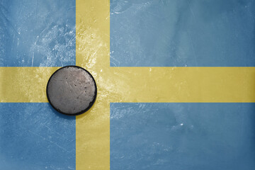 old hockey puck is on the ice with national flag of sweden .