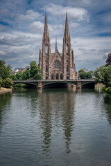 Fototapeta na wymiar Strasbourg, France - 06 28 2023: View of the facade of St. Paul's Reformed Church reflecting on the water.