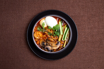 Bowl of spicy Korean ramen with mushrooms, egg, cucumber, and cilantro.