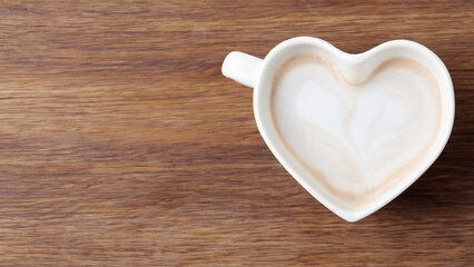 white mocka in a heart shaped cup on wooden background, wooden cafe layout